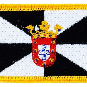 Puede incluir: Parche bordado con un diseño de bandera. La bandera tiene un patrón de cuadros blancos y negros y un escudo rojo con una corona dorada. El parche tiene un borde amarillo.