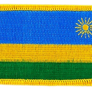 May include: A yellow, green, and blue embroidered patch with a yellow sun in the center. The patch is surrounded by a yellow border.