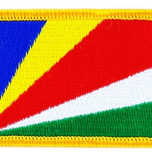 Peut inclure: Un écusson brodé représentant le drapeau des Seychelles. Le drapeau est de couleur bleu, jaune, rouge, blanc et vert avec une bordure jaune.