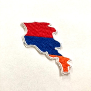 Op de afbeelding: Een geborduurde patch in de vorm van de omtrek van Armenië met de kleuren van de Armeense vlag: rood, blauw en oranje.