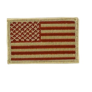 Op de afbeelding: Een klein geborduurd Amerikaans vlagpatch met een tan rand en een rood, wit en blauw ontwerp.