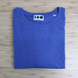 May include: A blue t-shirt with a textured pattern and a black and white label that reads "I+O ONE AND OTHER.IO"