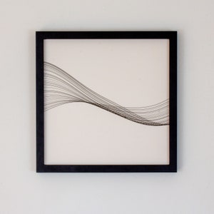 May include: Black framed wall art with a white background and a black line design that resembles a wave.
