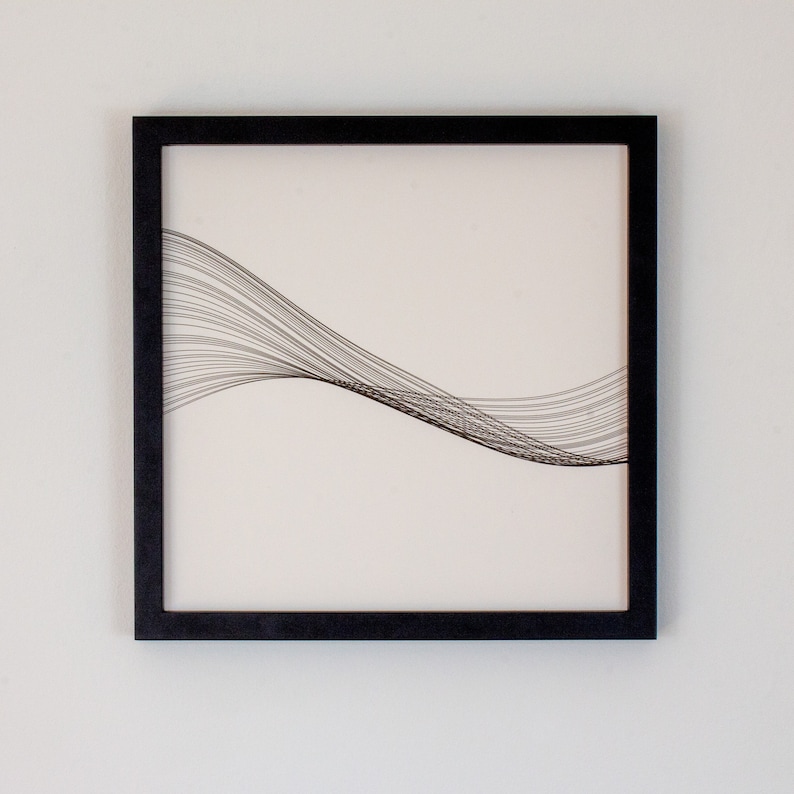 May include: Black framed wall art with a white background and a black line design that resembles a wave.