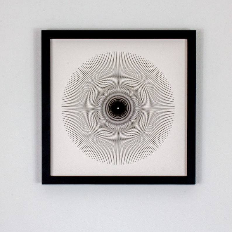 May include: A black framed print with a white background and a black and white geometric design of concentric circles radiating outward from the center.