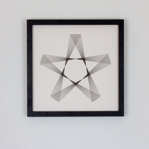 May include: A black framed print with a geometric design of a star made of thin lines.