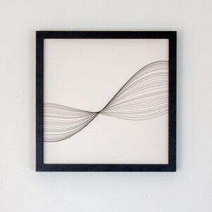 May include: Black framed wall art with a white background and a design of thin black lines forming a wave shape.