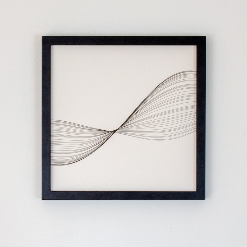May include: Black framed wall art with a white background and a design of thin black lines forming a wave shape.