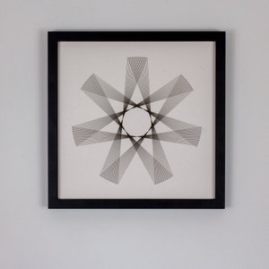 May include: Black framed wall art featuring a geometric design of intersecting lines creating a starburst pattern.