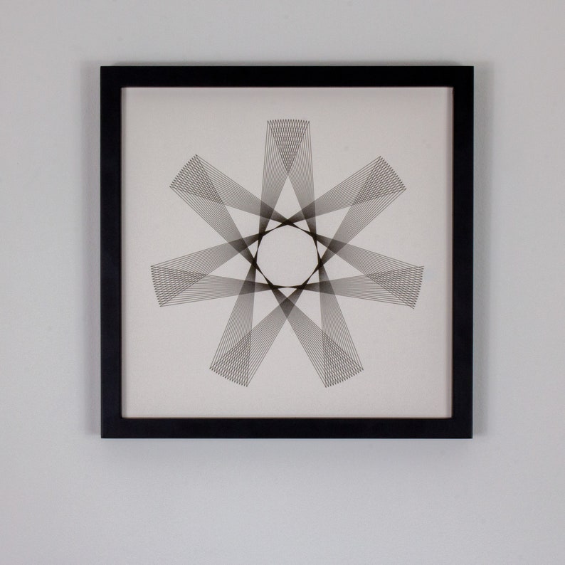 May include: Black framed wall art featuring a geometric design of intersecting lines creating a starburst pattern.