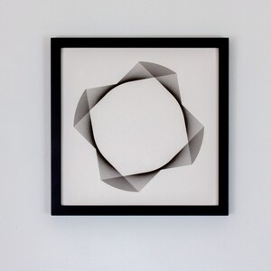 May include: A black framed artwork featuring a geometric design of overlapping gray shapes forming a circle in the center.