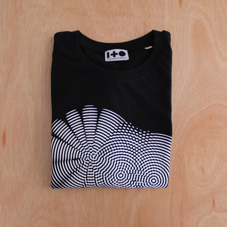 May include: Black t-shirt with a white graphic print of a circular pattern. The shirt has the text "1+O ONE AND OTHER.IO" on the front.