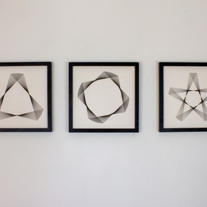 May include: Three black framed prints with white backgrounds and geometric designs. The designs are a triangle, a circle, and a star.