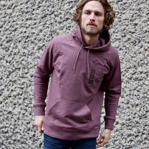 Op de afbeelding: Een bordeauxrood hoodie met een verticale rij van vijf zwarte geometrische ontwerpen op de voorkant.
