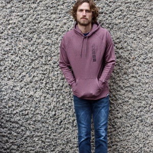 Op de afbeelding: Een maroon hoodie met een verticale rij symbolen die op de voorkant zijn gedrukt. De symbolen omvatten een cirkel, een vierkant, een driehoek en een rechthoek.