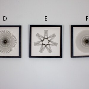 May include: Three framed black and white abstract geometric designs. The designs are all circular and feature a central point. The frames are black and have a white mat.
