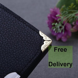 May include: Close-up of a black leather journal with gold corner accents. The journal has a textured surface and a decorative design. Free Delivery text is visible in the background.