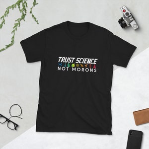 May include: Black t-shirt with white text that reads "TRUST SCIENCE NOT MORONS". The text is surrounded by colorful science-related icons.