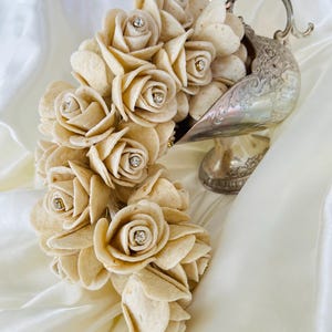 Può includere: Un bouquet di rose bianche di tortilla con strass in una zuppiera d'argento. Le rose sono disposte a cascata, con i gambi delle rose nascosti all'interno della zuppiera.