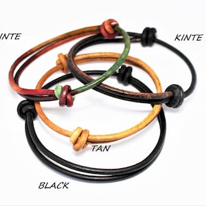 May include: Three leather bracelets in black, tan, and a multi-colored kinte pattern. The bracelets are tied together with knots.