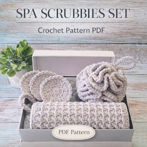 May include: A spa scrubbies set in a gift box. The set includes a crocheted bath pouf, washcloths, and a long, rectangular scrubby. The items are light gray and the box is white. Text on the image reads "SPA SCRUBBIES SET" and "Crochet Pattern PDF".