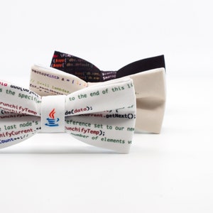 May include: Three bow ties with a white background and code printed on them. The bow ties are in different colours: black, beige, and white. The white bow tie has a small coffee cup icon with steam coming out of it.