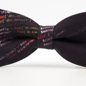 K&ouml;nnte beinhalten: Ein schwarzer Fliege mit einem Muster aus farbigem Code. Der Code enth&auml;lt den Text "(Sapp['dbs.optr" und "(Sapp['dbs.default:".