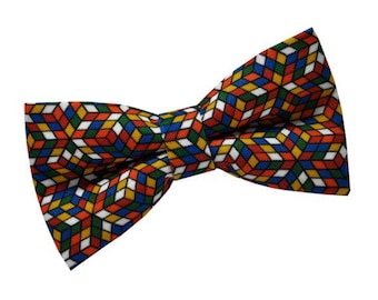 May include: A colorful bow tie with a geometric pattern of red, blue, green, yellow, and white squares. The pattern resembles a Rubik's Cube.