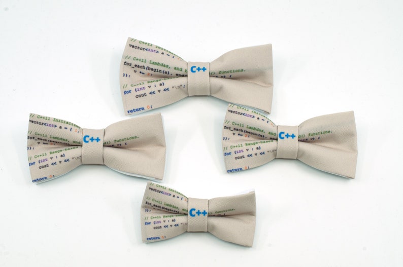 May include: Four beige bow ties with a C++ logo and code printed on them. The bow ties are arranged in a staggered pattern on a white background.