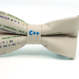 May include: A beige bow tie with a C++ logo and code printed on it. The code includes C++11 Initializer, Lambdas, and Range-based for loops.
