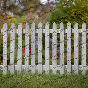 May include: A white picket fence with a blurred background of a garden with colourful flowers.