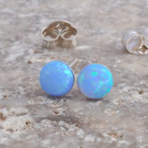 May include: A pair of silver stud earrings with light blue opal stones.