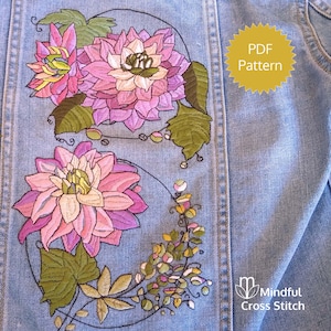 Può includere: Primo piano di una giacca di jeans blu chiaro con un ricamo floreale. Il ricamo comprende fiori rosa, viola e gialli con foglie verdi. Una grafica a stella gialla recita "PDF Pattern". Il logo Mindful Cross Stitch è visibile.