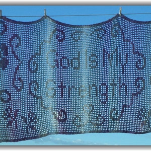 May include: A crocheted banner with the words "God is my strength" in purple yarn against a blue sky background.