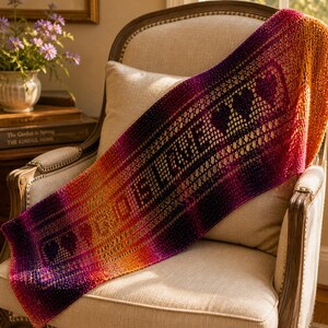 May include: A rectangular crochet shawl featuring a vibrant gradient of purple, magenta, and orange yarn. The openwork fabric displays the word BELIEVE in a repeating pattern, interspersed with heart shapes, creating a textured, colorful textile.