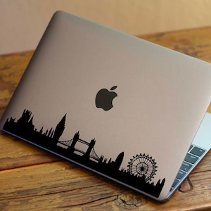 Puede incluir: Un port&aacute;til plateado con una pegatina en silueta negra del horizonte de Londres, incluyendo el London Eye, el Big Ben y el Tower Bridge.