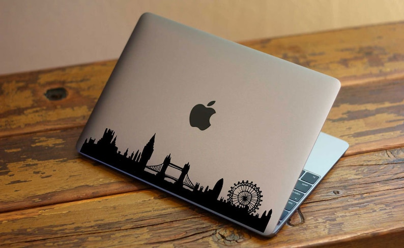 Puede incluir: Un port&aacute;til plateado con una pegatina en silueta negra del horizonte de Londres, incluyendo el London Eye, el Big Ben y el Tower Bridge.