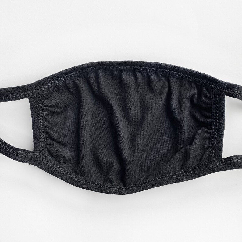 May include: A black face mask made of soft fabric with elastic ear loops. The mask is plain and has no design or pattern.