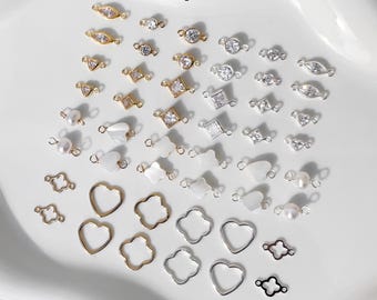 May include: A collection of 48 connector pieces in gold and silver tones. The kit includes various shapes such as hearts, flowers, and geometric designs, some adorned with clear gemstones and pearls. The text reads "Connector Starter Kit" and "14k Gold Filled & Sterling Silver."