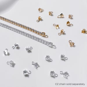 May include: A gold and silver CZ chain with various gold and silver jewelry findings scattered on a white surface. The text "CZ chain sold separately" is visible at the bottom.