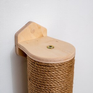 Puede incluir: Un rascador para gatos de madera con una cuerda de sisal que lo cubre. El poste est&aacute; fijado a la pared con un soporte de madera. El soporte tiene una forma redondeada y un peque&ntilde;o agujero en el centro.