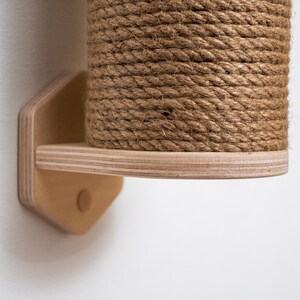 Puede incluir: Un rascador para gatos de madera con una cubierta de cuerda natural. El poste est&aacute; montado en una pared con un soporte de madera.