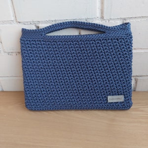 Peut inclure: Un sac en crochet bleu avec une seule anse. Le sac porte une petite étiquette indiquant "CutecraftBLT".