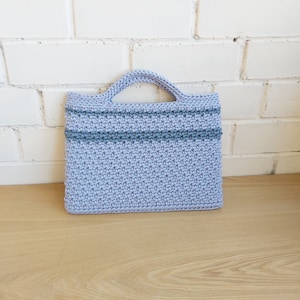 Peut inclure: Un sac cabas en crochet bleu clair avec deux bandes bleu foncé. Le sac a une seule anse.