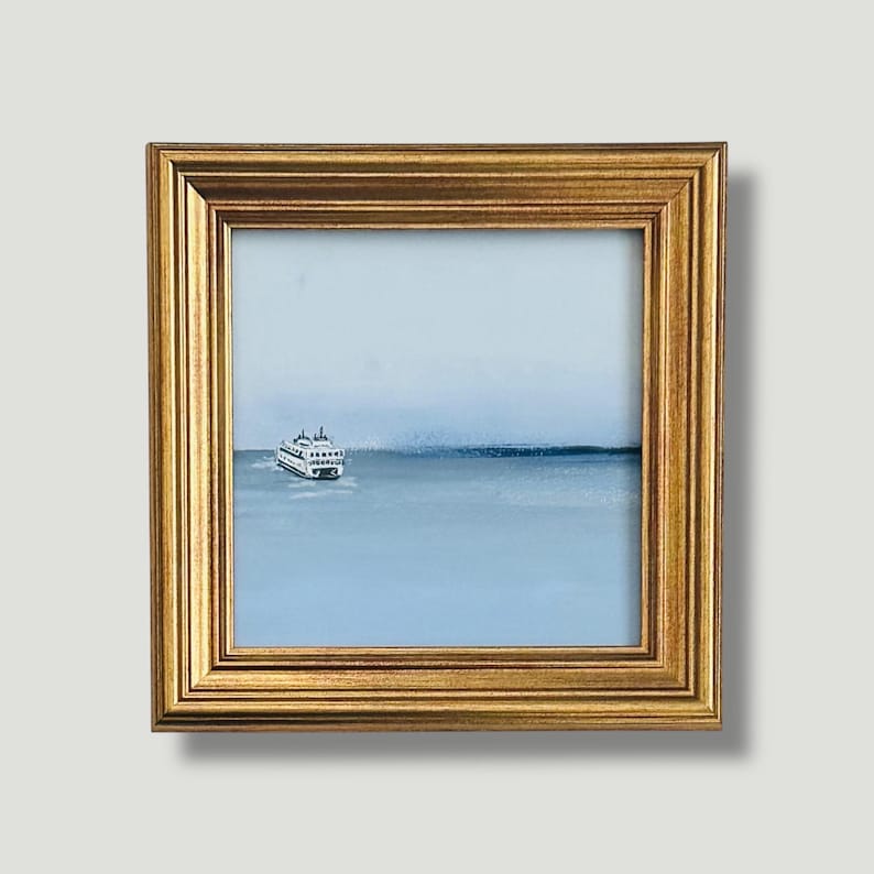 K&ouml;nnte beinhalten: Gerahmtes Gem&auml;lde eines F&auml;hrschiffs auf hellblauem Meer. Das Boot ist wei&szlig; mit schwarzen Details. Das Gem&auml;lde befindet sich in einem goldfarbenen Rahmen.