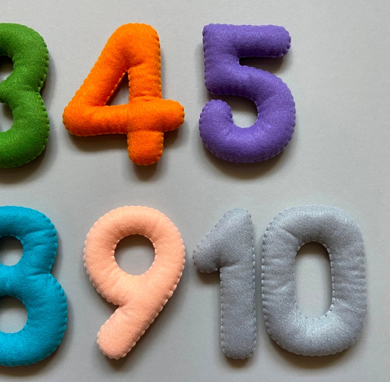 May include: Felt numbers 3, 4, 5, 8, 9, 10 in various colours. The numbers are stitched with a white thread.