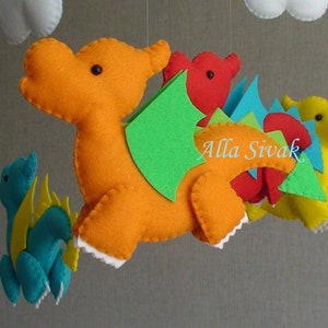 May include: A felt mobile with four colorful dragons. The largest dragon is orange with green wings and a red tail. The other dragons are red, blue, and yellow.
