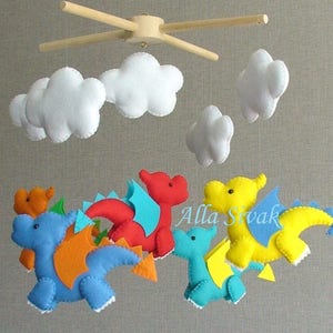 May include: A baby mobile with five felt dragons in blue, red, yellow, and orange, with white felt clouds hanging above them.