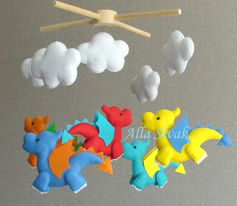 May include: A baby mobile with five felt dragons in blue, red, yellow, and orange, with white felt clouds hanging above them.
