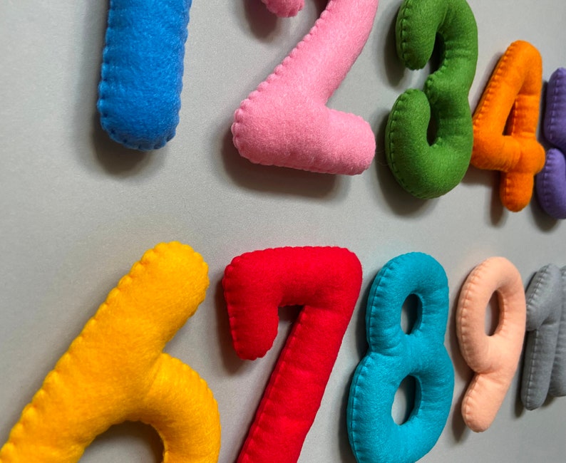 May include: Felt numbers from one to nine in different colours. The numbers are sewn together with a zig-zag stitch.